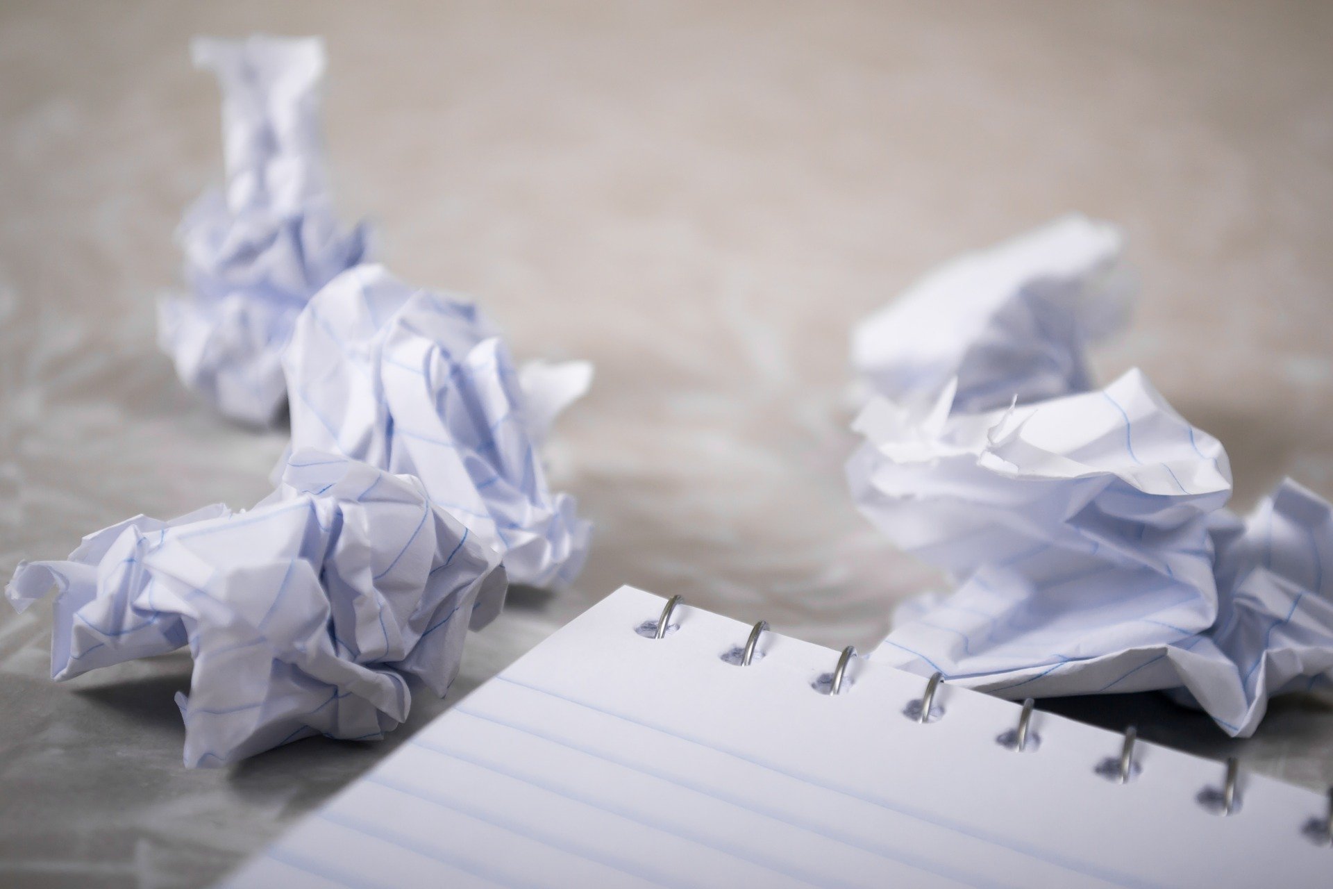 Notebook surrounded by pieces of crumpled paper