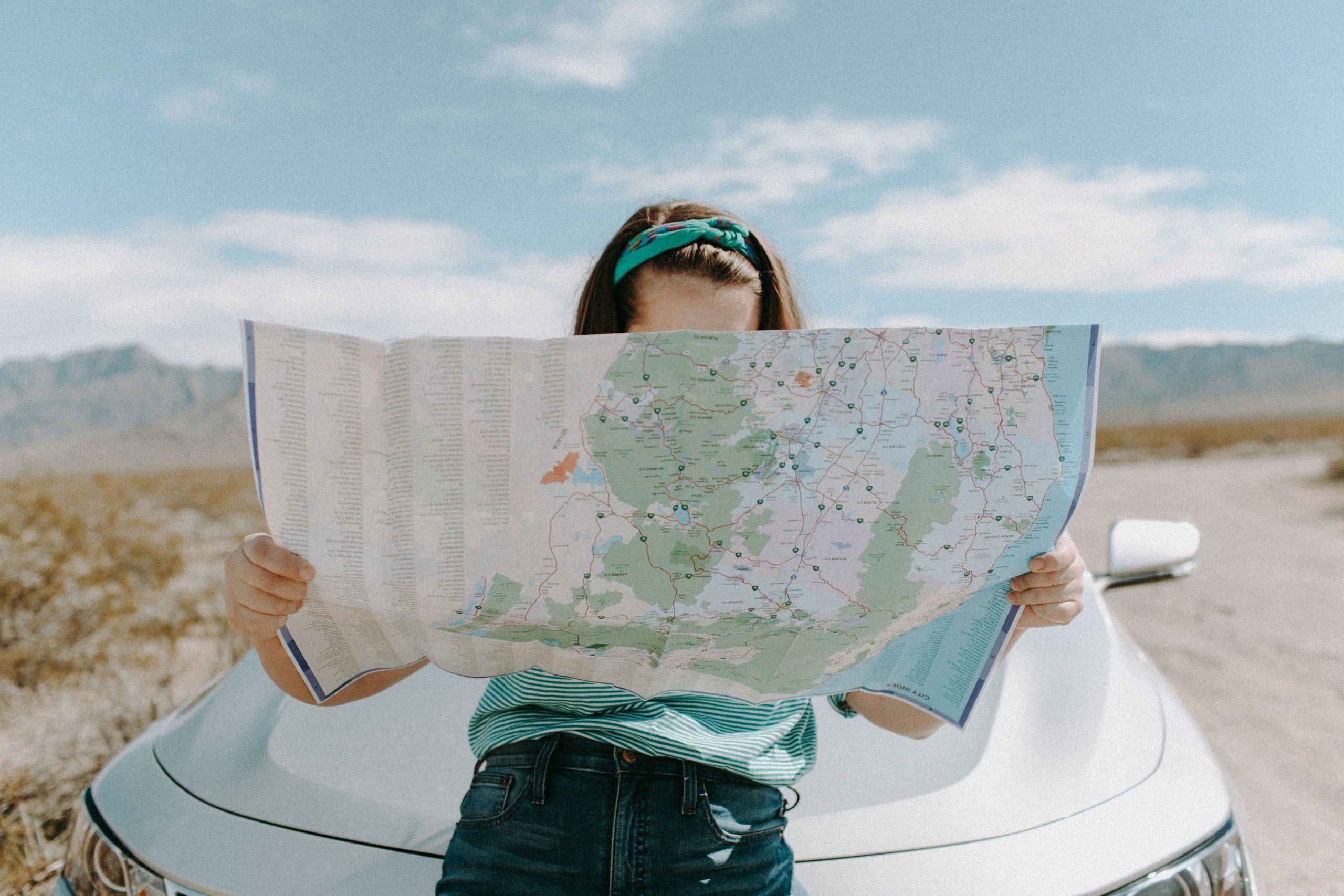 Young woman looking at a paper map on a dirt road