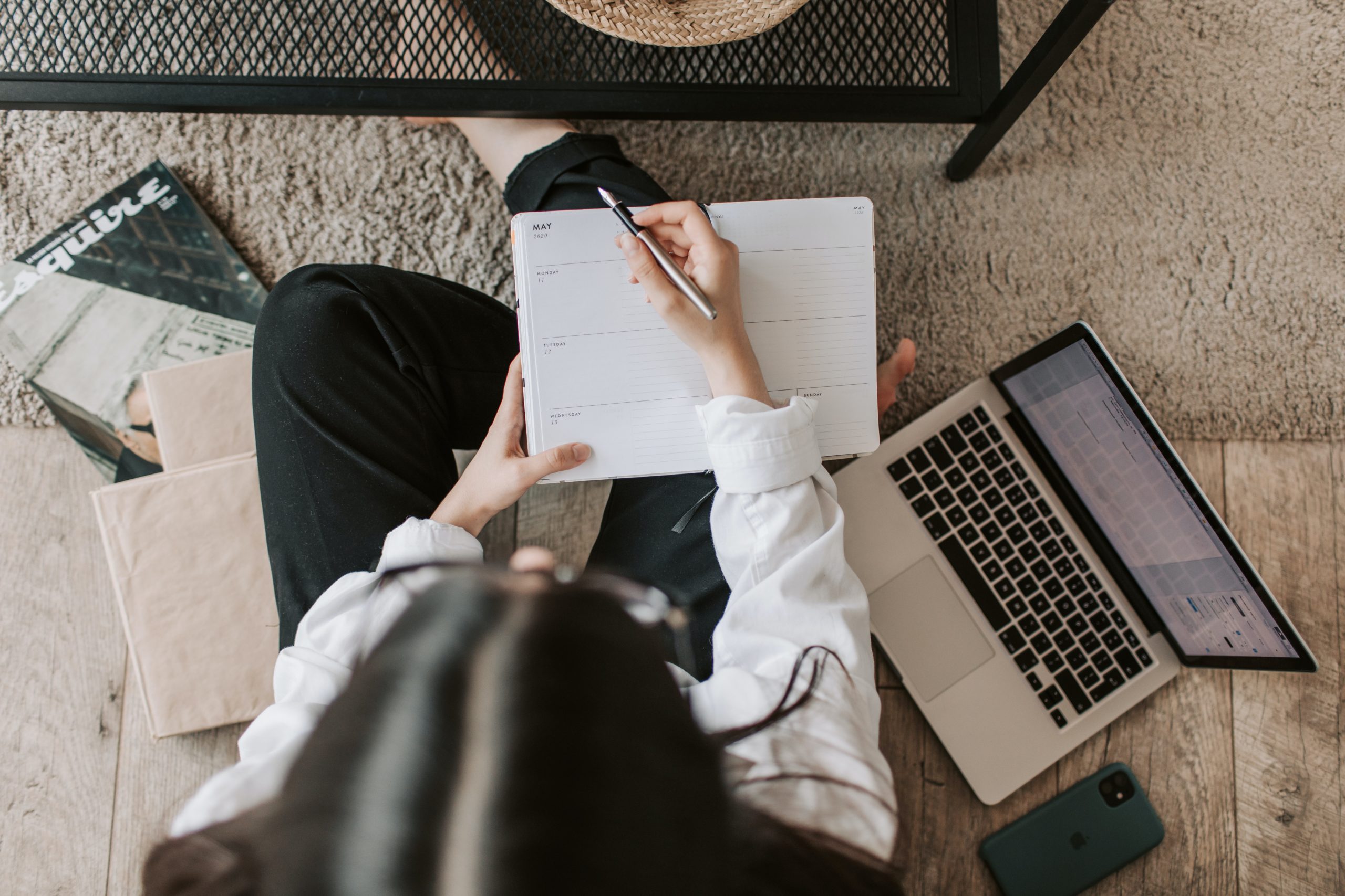 Young woman with calendar and open laptop sitting on the floor