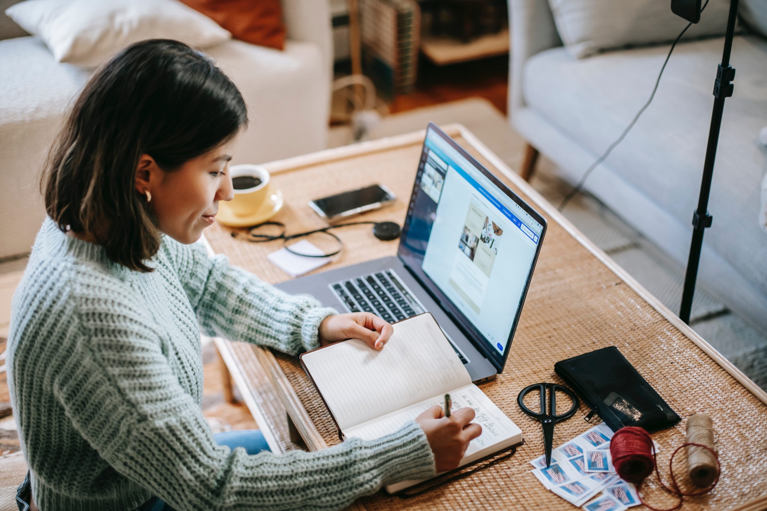 Young woman doing research on her laptop and taking notes