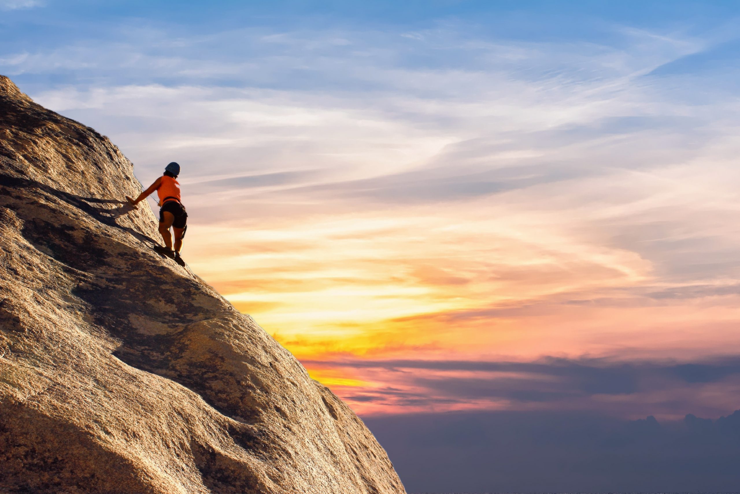 Climber at the top of a mountain at sunset